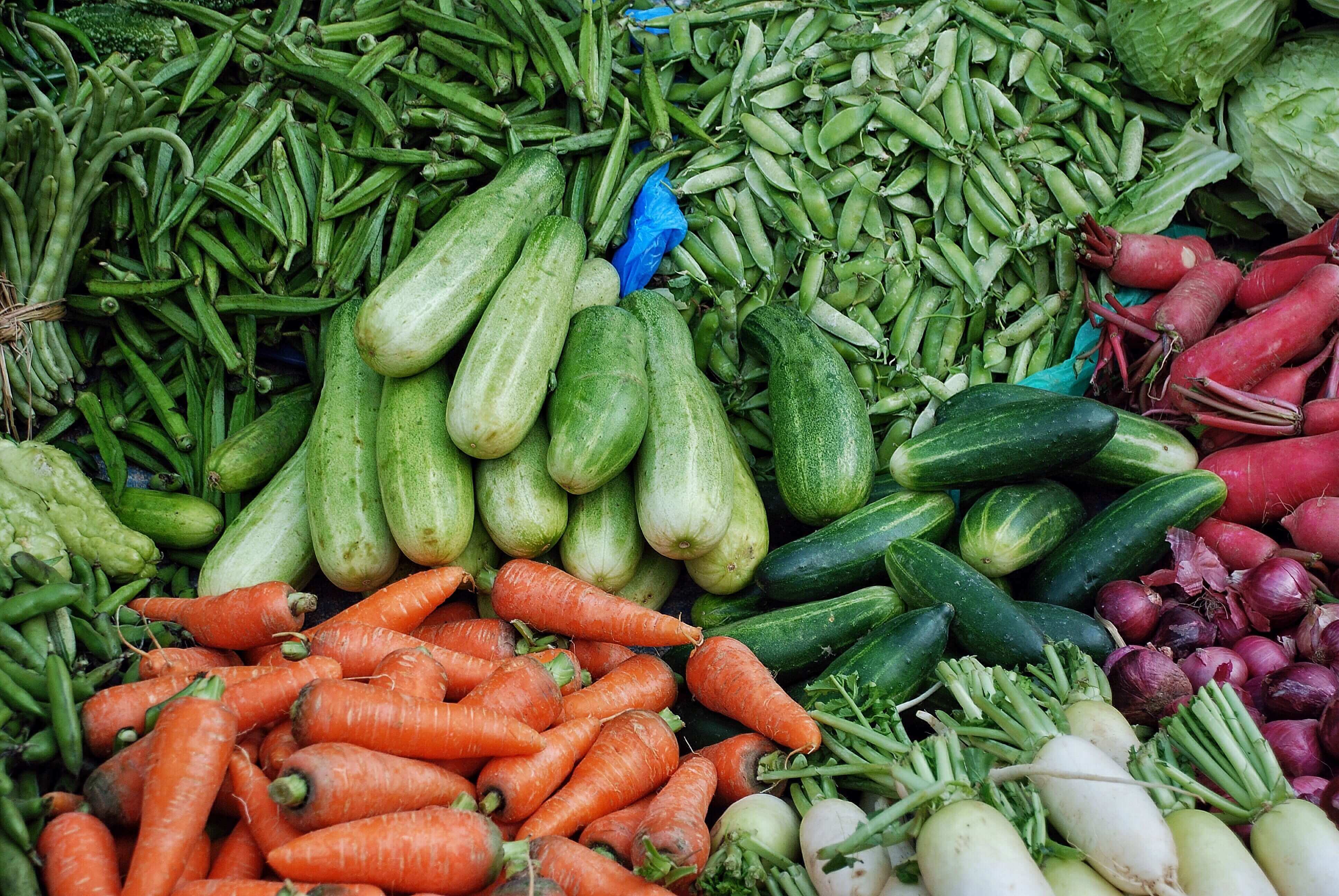 variety of fresh produce, including carrots, cucumbers and peas, at the grocery store