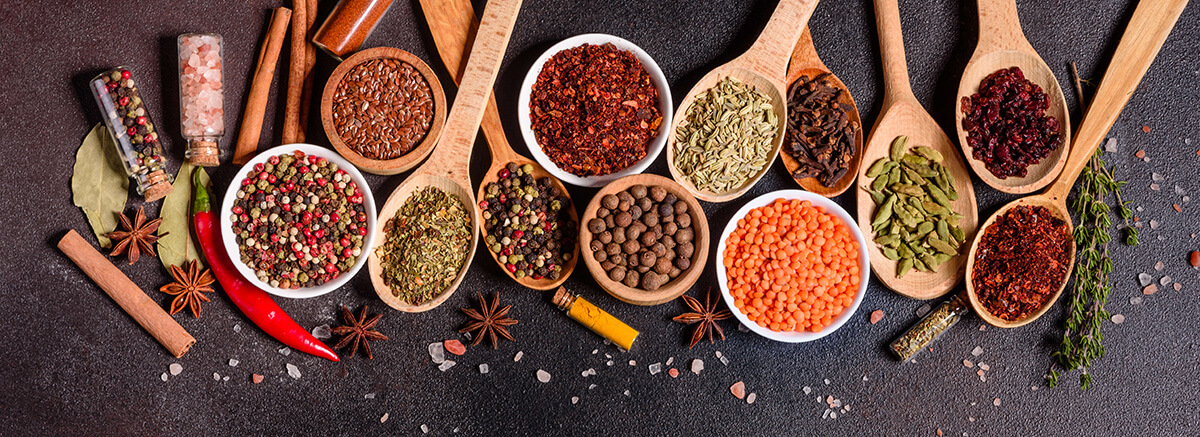 assortment of indian spices displayed in wooden spoons and bowls