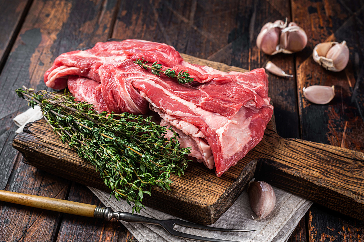 raw, boneless cut of lamb neck meat on wooden slab